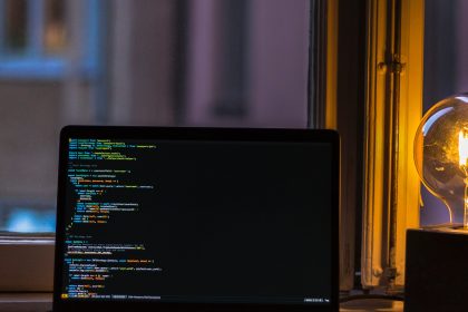 Notebook mit Code auf dem Bildschirm stehend auf einer Fensterbank